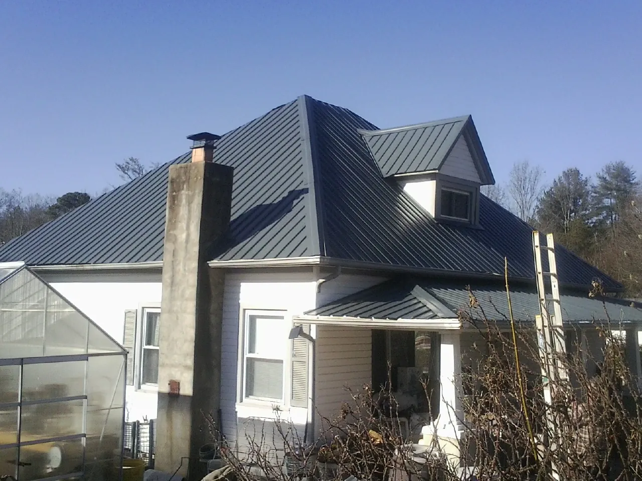 Dark blue standing seam metal roof on a white farmhouse with dormer — Slate & Tile Roof Repair by Roofing Brothers in Crucible