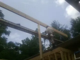 Carpenter setting a ridge beam over a new addition frame — Ice Dam Removal by Roofing Brothers in Crucible