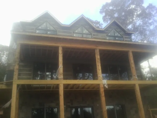 Dormers and porch framing on a large log home under construction — Roof Coating work by our crew in Crucible