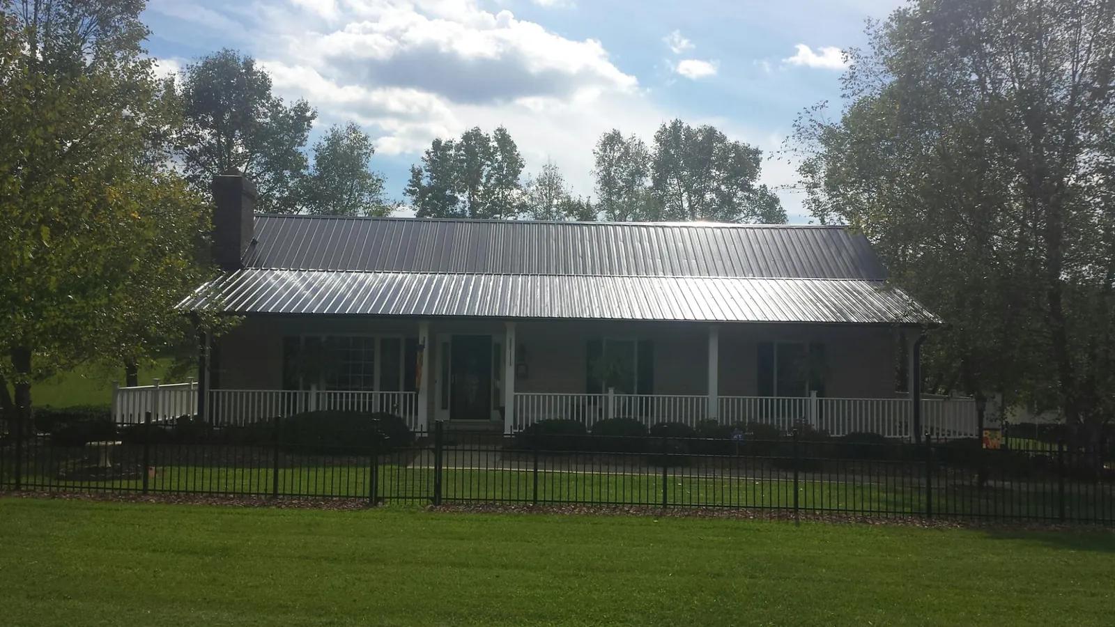 Gray metal roof on a brick ranch with a full width front porch — Gutter Guard Installation work by our crew in Crucible
