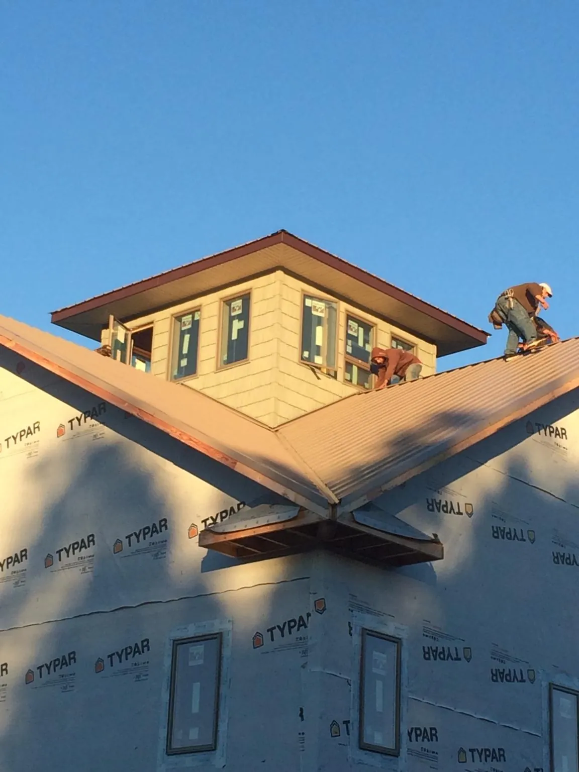 Roofers working around a rooftop cupola on a new metal roof at sunset — Roof Waterproofing in Crucible by Roofing Brothers